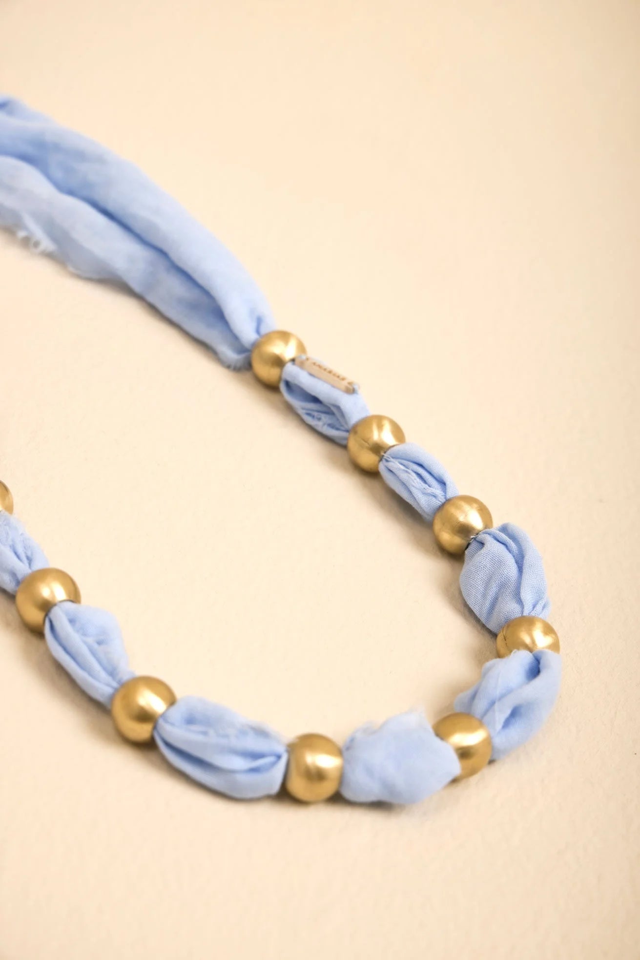 Collar Latido ANARIAS Atelier usado sobre camisa — detalle de acabado en bronce
