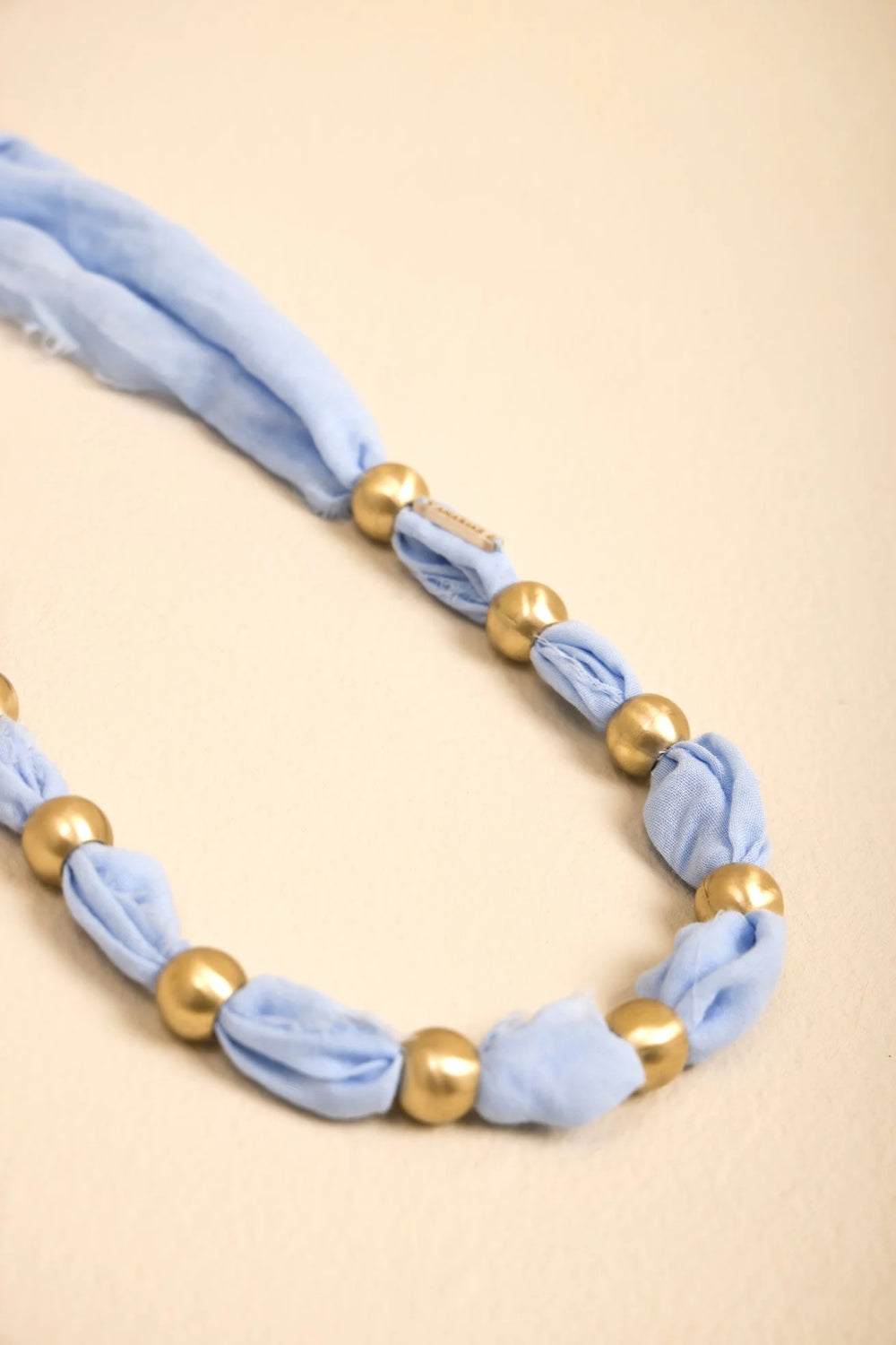 Detalle del Collar Latido ANARIAS Atelier — bolas de bronce sobre tela, tono blanco